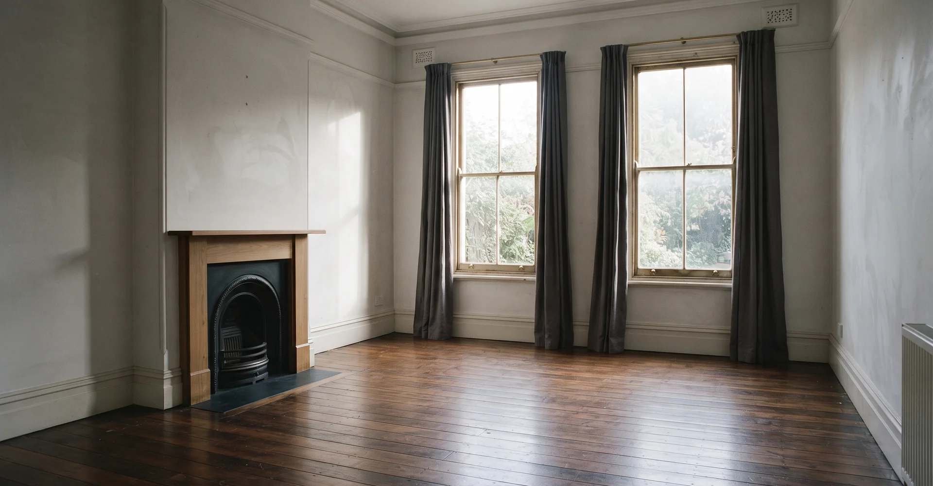 Empty sunlit heritage living room with bare polished floors after an estate clearance