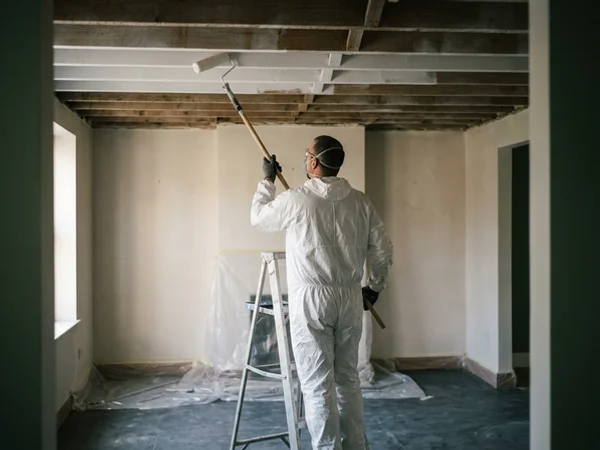 Roller applying shellac encapsulant to bare ceiling joists